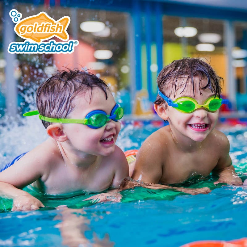 Two children smile while in pool with googles on