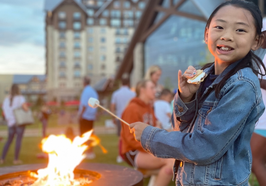 Gaylord Rockies Child at fire pit cooking and eating a S'mores