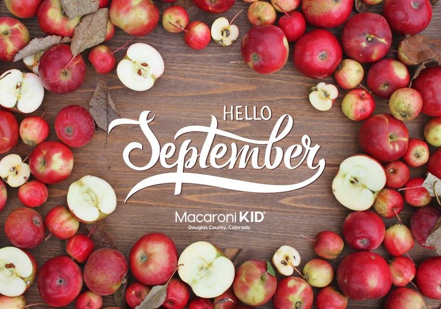 dozens of apples on a wooden table with hello september written in the middle and the macaroni kid douglas county logo