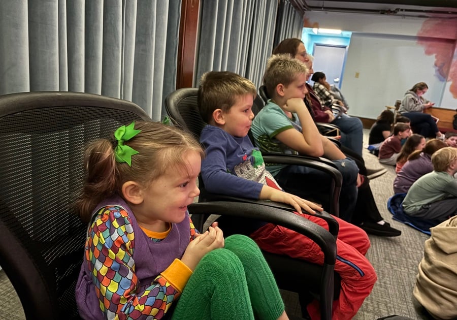 Three young children sit wide-eyed and smiling as they watch The Golden Goose at Gamut Theatre, fully immersed in the performance.