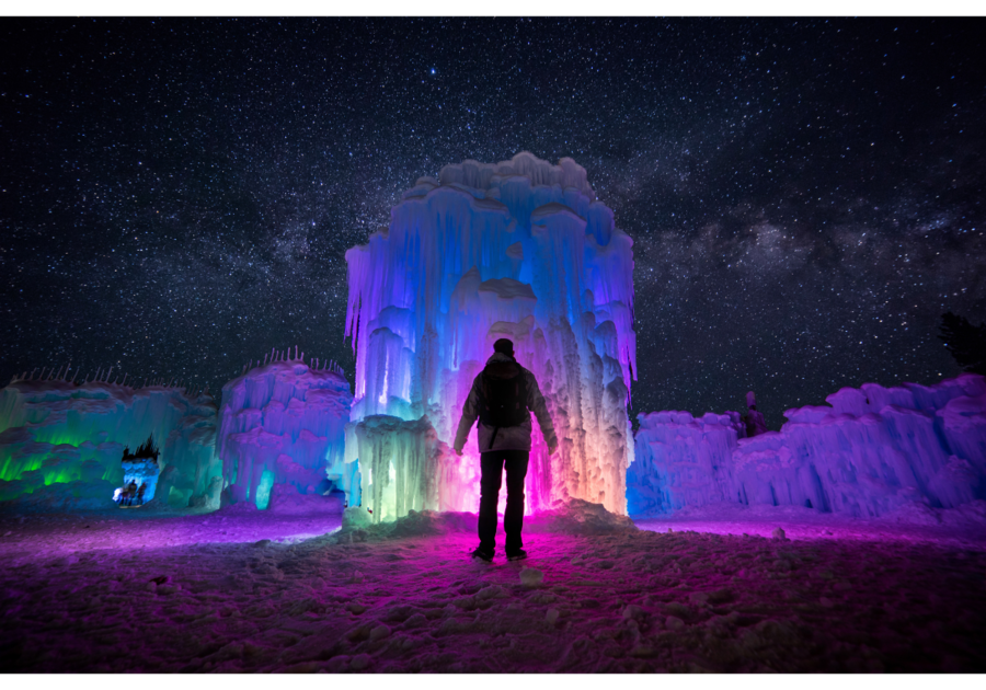 Person standing in front of Ice Castles at night