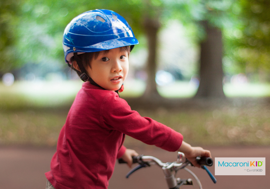 Little Boy is wearing a bashful smile on bike.