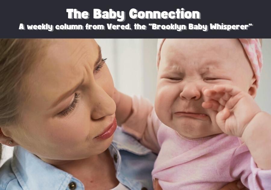 Mother looks worried and consoling while holding crying baby