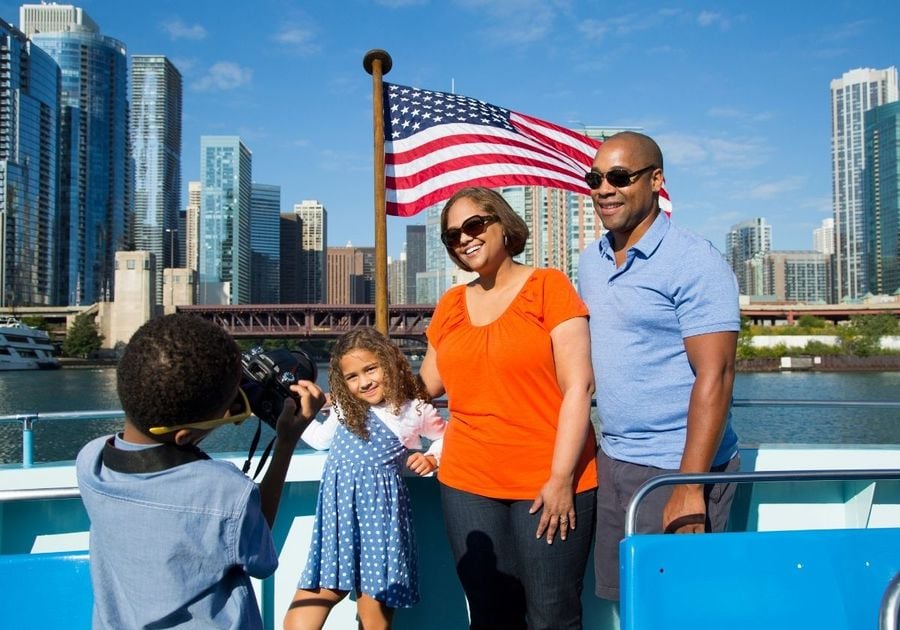 Family poses for photo with Chicago skyline in background - aboard Mercury Cruises