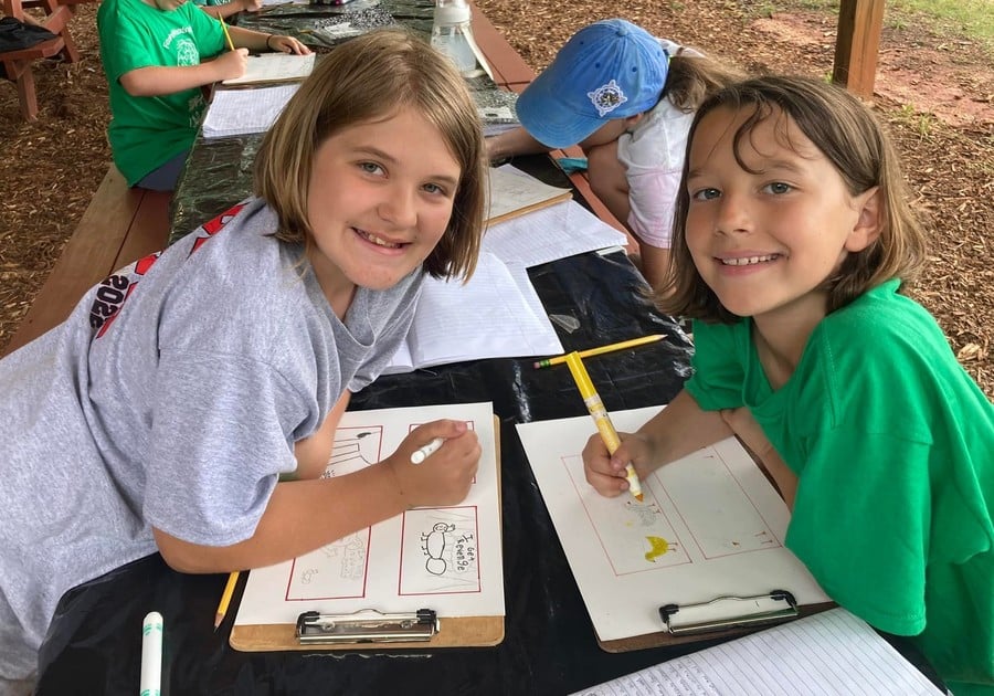 photo of female campers working on paper work at table