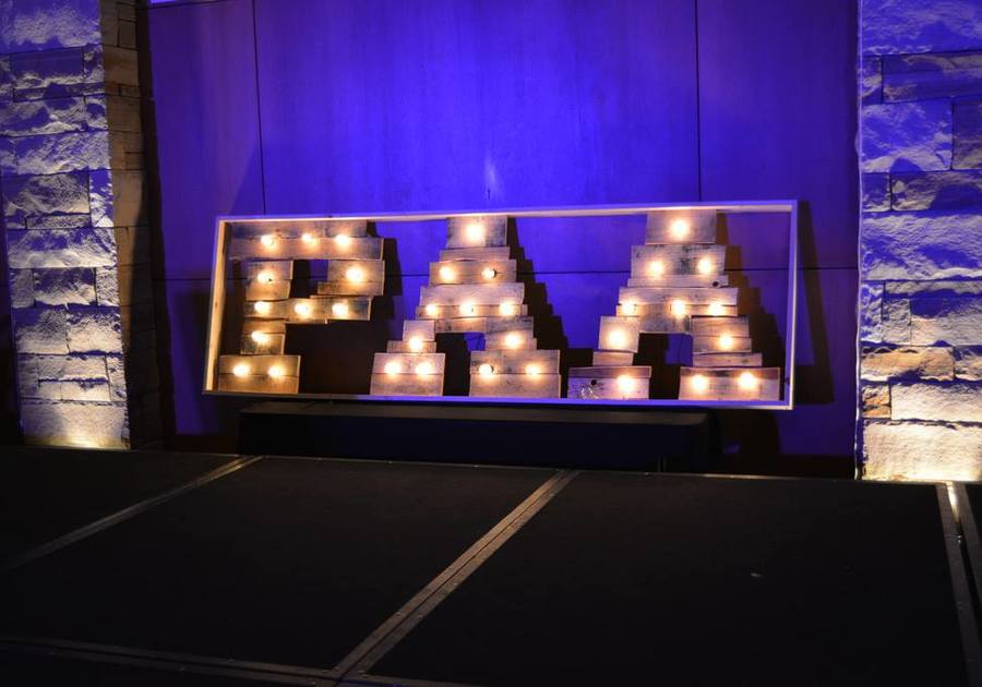The letters PAA in lights in front of a purple backdrop