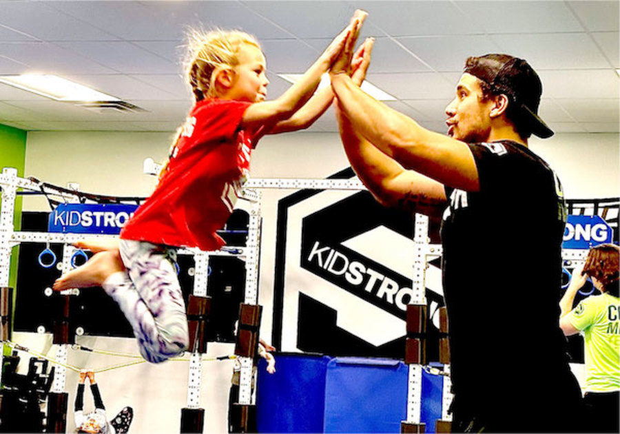 child and coach double high five in a kidstrong class