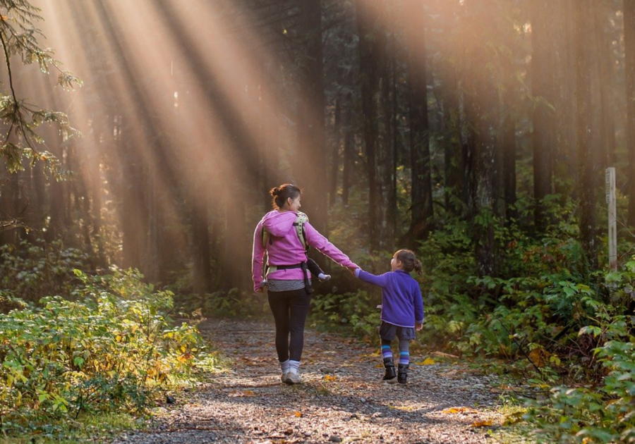 Mom and daughter walking outside on wooded path way