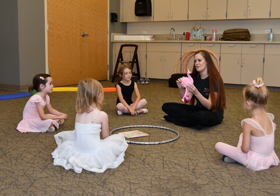 4 young girls sitting on the floor with their dance instructor