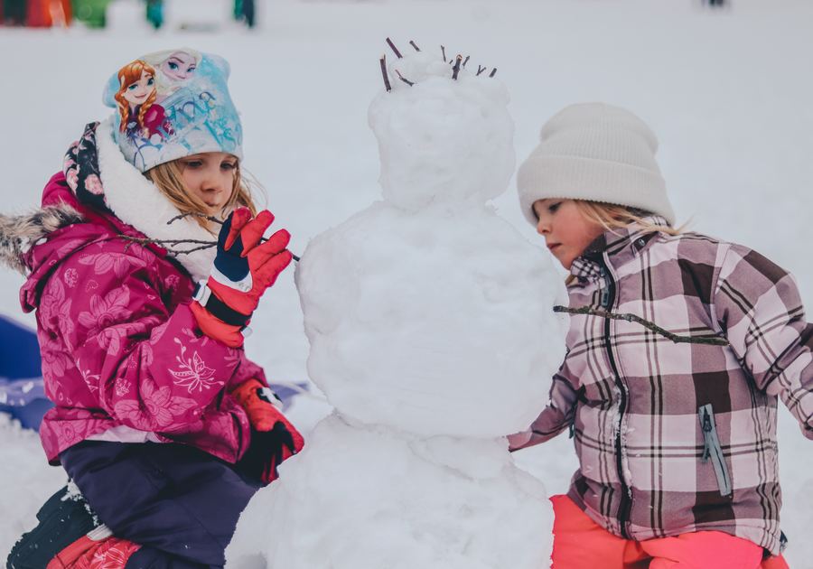 girls playing in the snow wearing winter gear