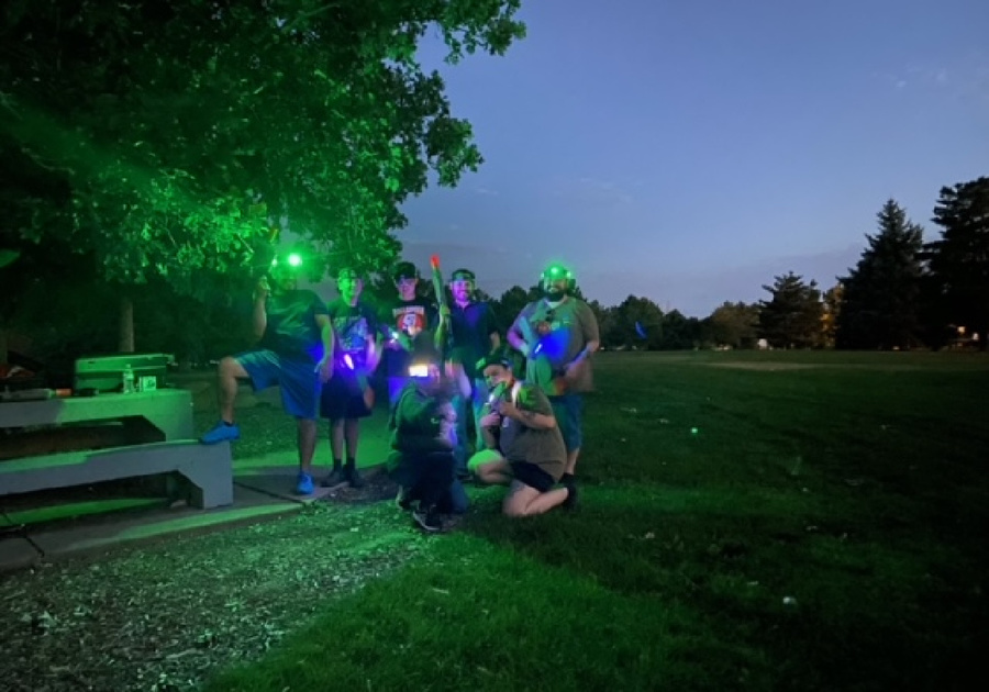 a group of people in a park at dusk playing laser tag