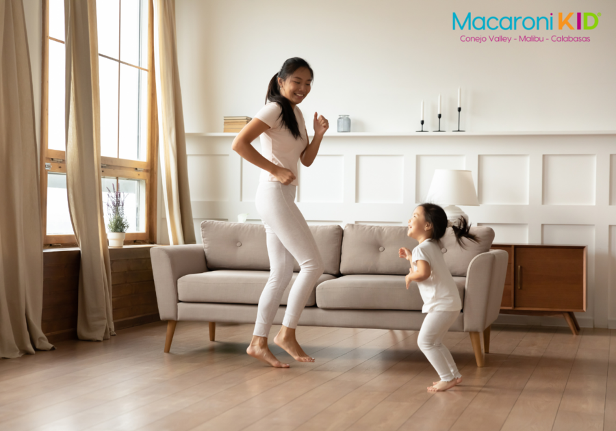 mom dancing at home with young daughter in the living room