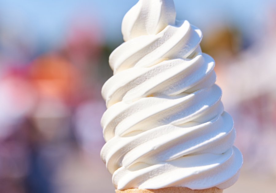 Vanilla ice cream swirl on a cone with outdoors on a blurred background