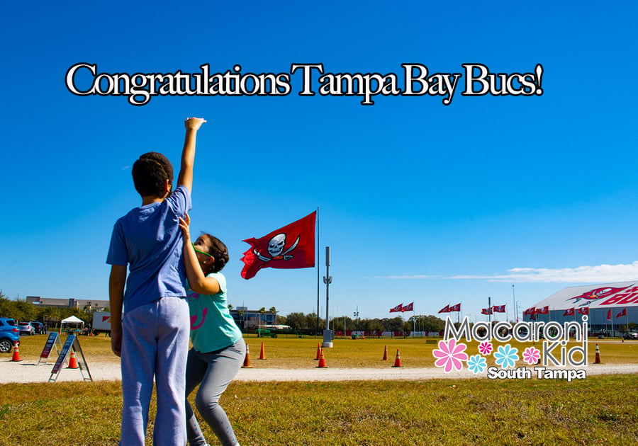 Boy with arm raised to the sky and bucs flag in background