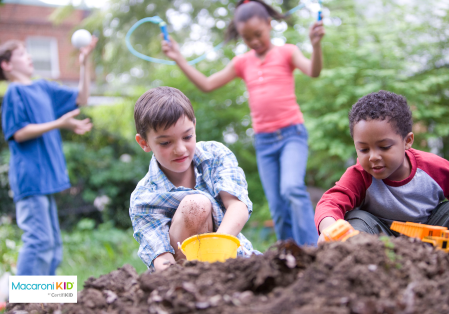 four children playing outside in a backyard dirt pile