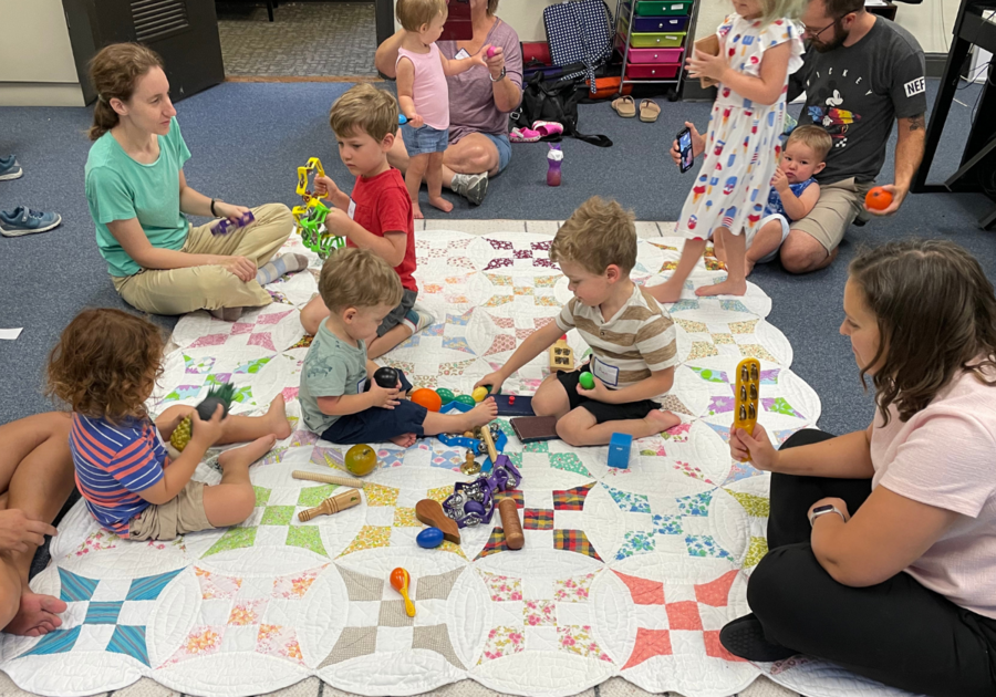toddlers playing with musical instruments on blanker