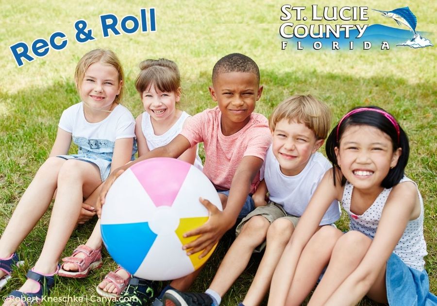 young children sitting outside with one holding a beach ball