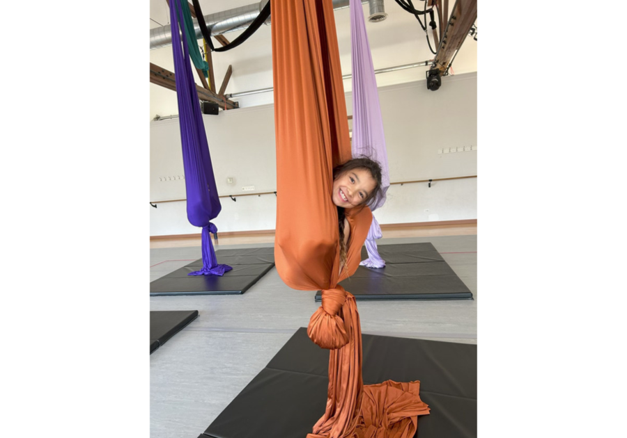 kid poking face out of aerial silks