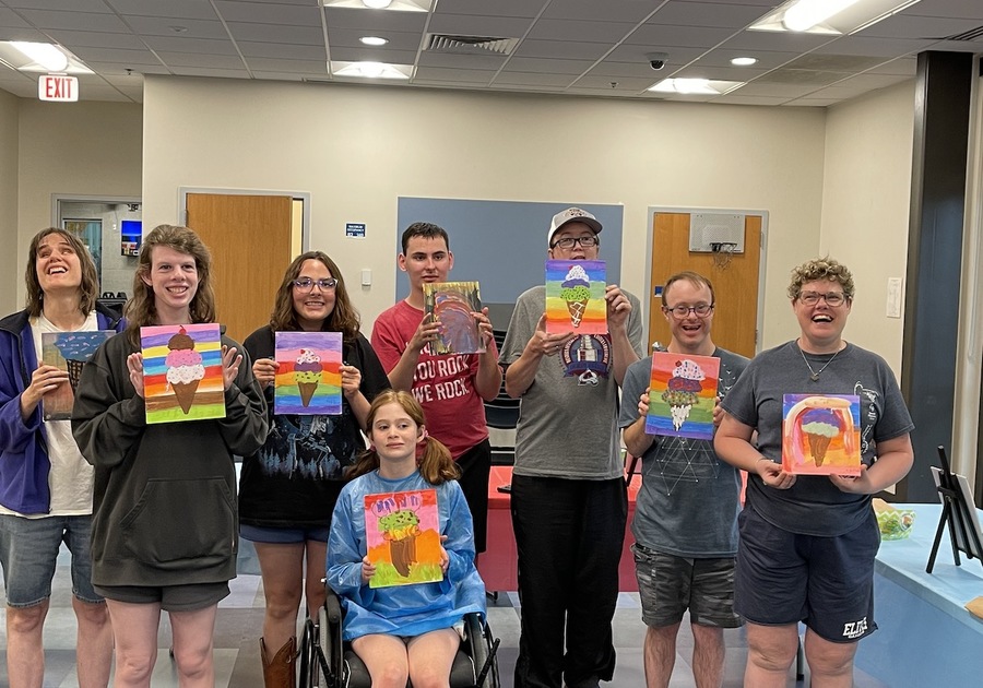 group of young adults and teens showing their artwork after a therapeutic recreation painting class