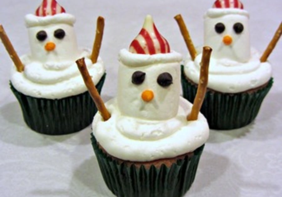 Three chocolate cupcakes with white frosting snowmen on top