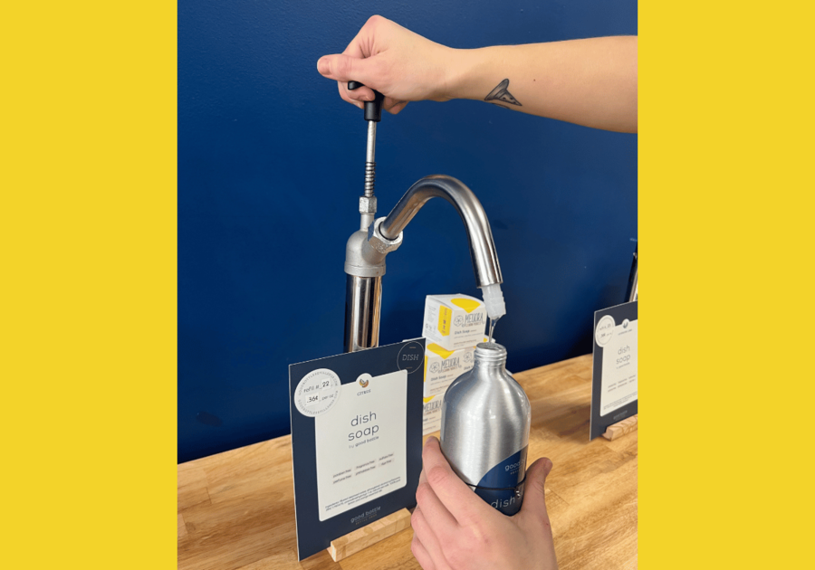 Good Bottle Refill Shop - dish soap container being refilled over a wooden counter