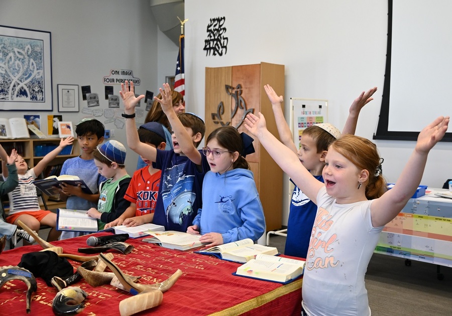 class of kids singing with hands in the air