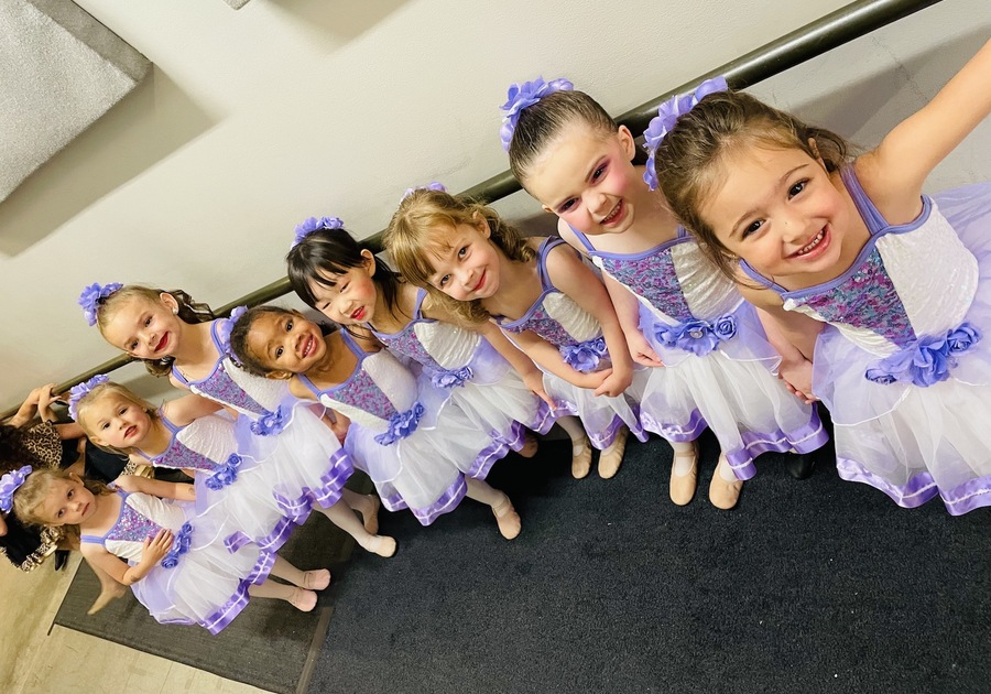 very young dancers dressed in dance costumes posing before a performance
