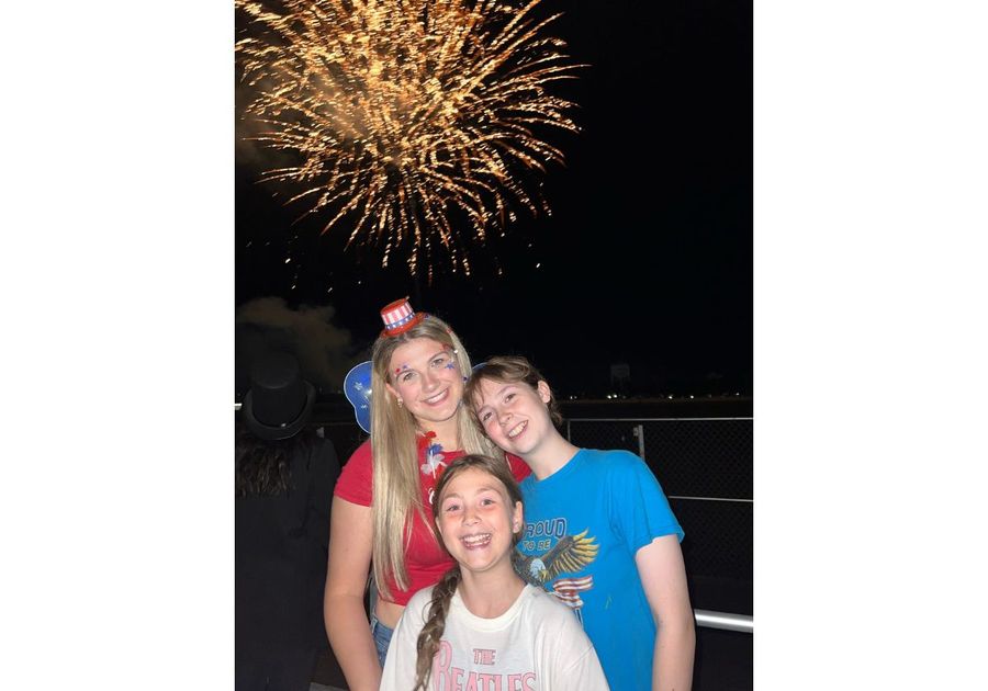 three teens with a firework exploding behind them