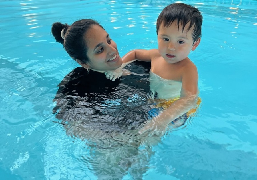 little boy in pool held by woman