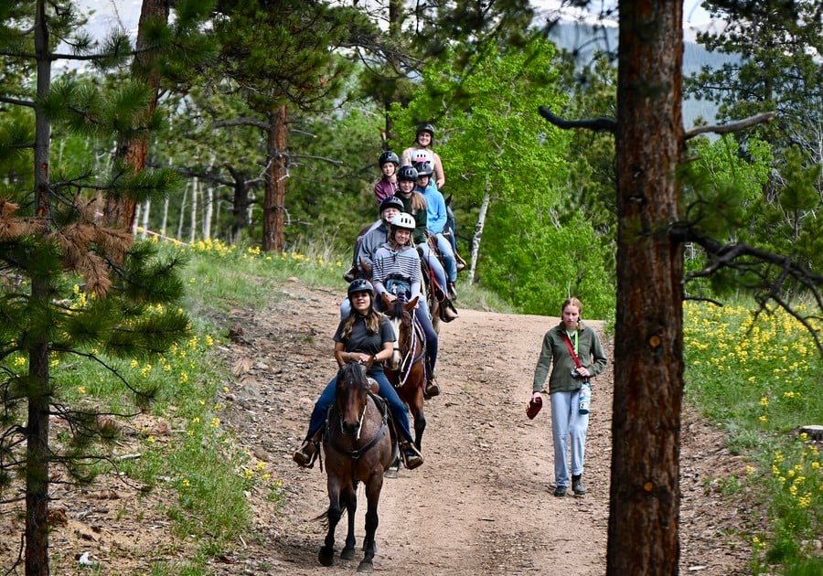 several girls trail riding on horseback at  Girl Scouts of Colorado summer camp