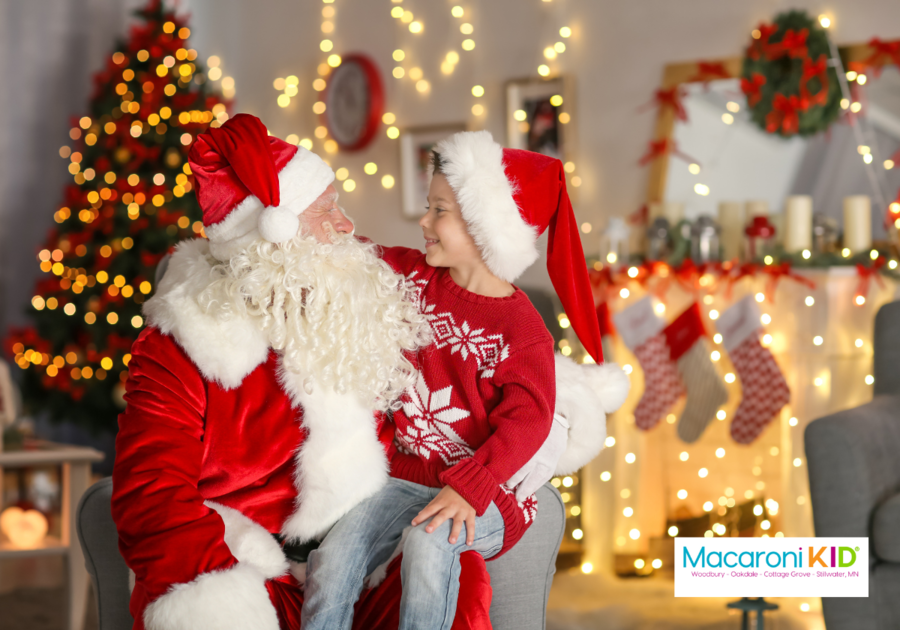 Little boy sitting on Santa's lap with Christmas decorations in the back