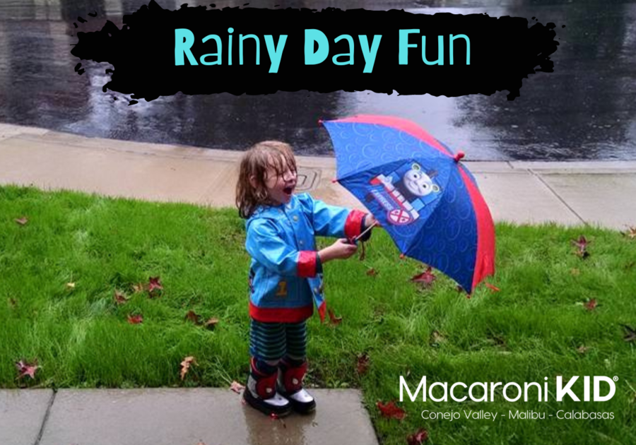 Rainy Day Fun, little boy having fun in the rain wearing a raincoat, rain boots and holding an umbrella