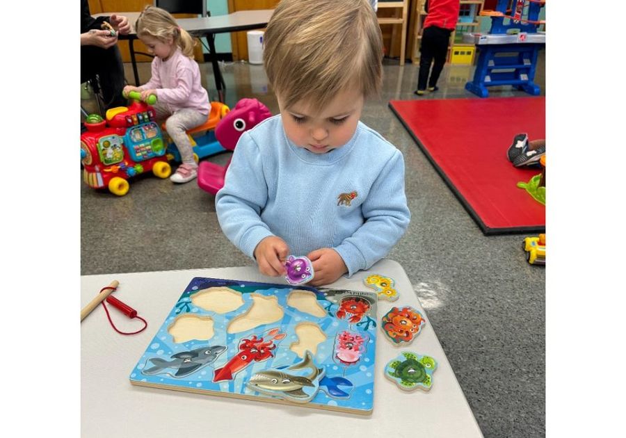 toddler playing with a wood puzzle