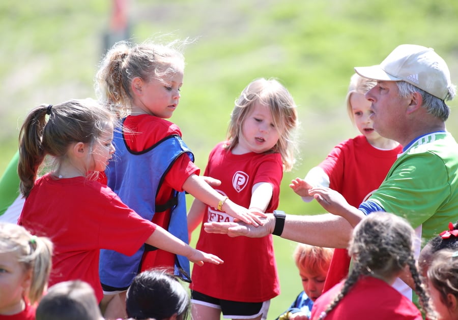 Penn Fusion Soccer Academy players and coach with hands in a huddle