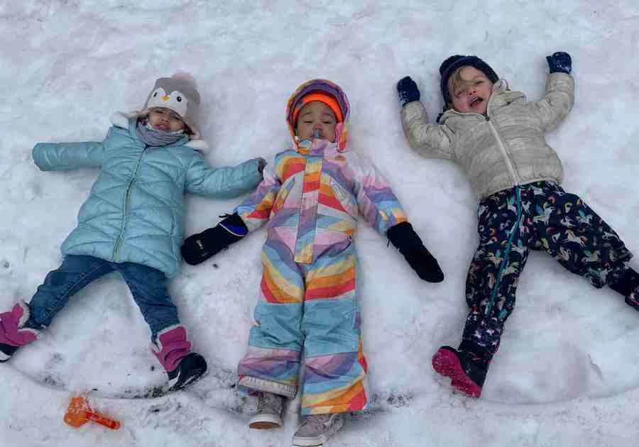 three kids making snow angels