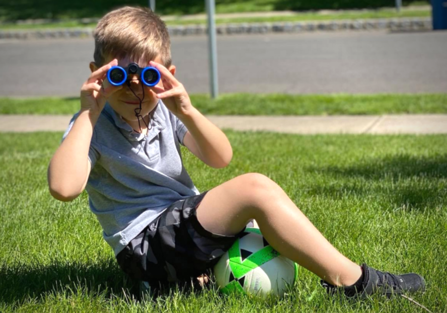 Kid sitting in yard looking through binoculars