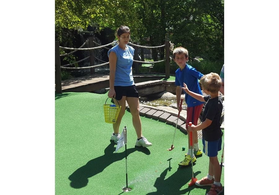 woman teaching two boys to putt