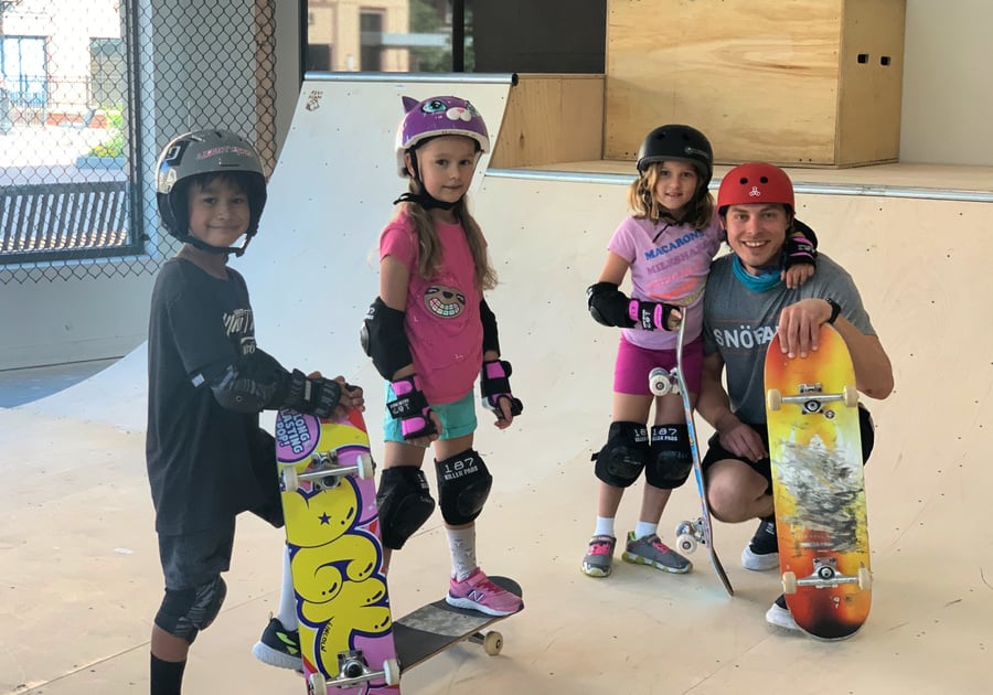 smiling children and instructor pose with skateboards at Snobahn summer camp