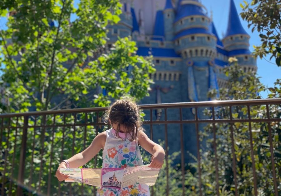 A young child looks at a map in front of Cinderella's Castle