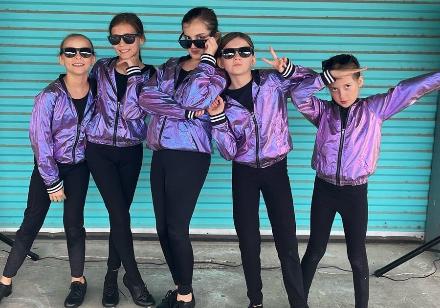 photo of female dancers in purple jackets and sunglasses