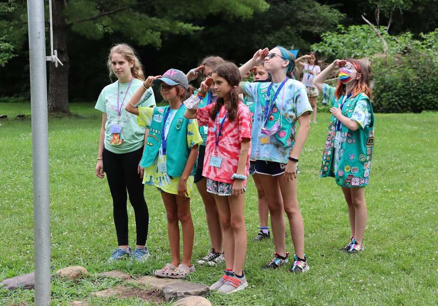 young girls at summer camp saluting the american flag at girl scout camp in va