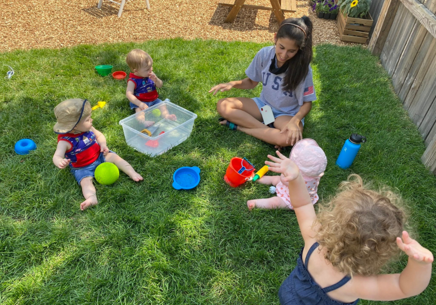 woman playing babies outside on grass with toys