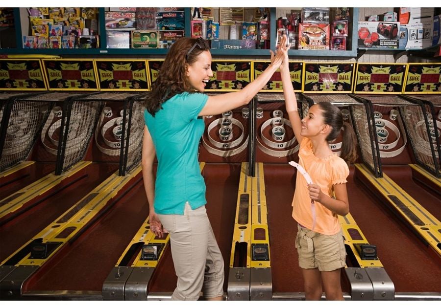 Mom and daughter high fiving in front of a Skeeball game