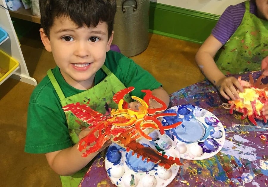 male camper holding up art project