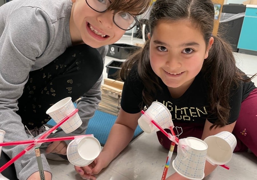 Two smiling kids building with straws and cups