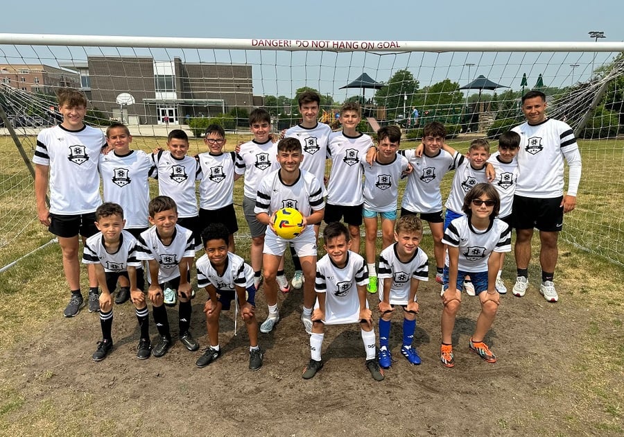 soccer team in black and white uniform posing in front of goal