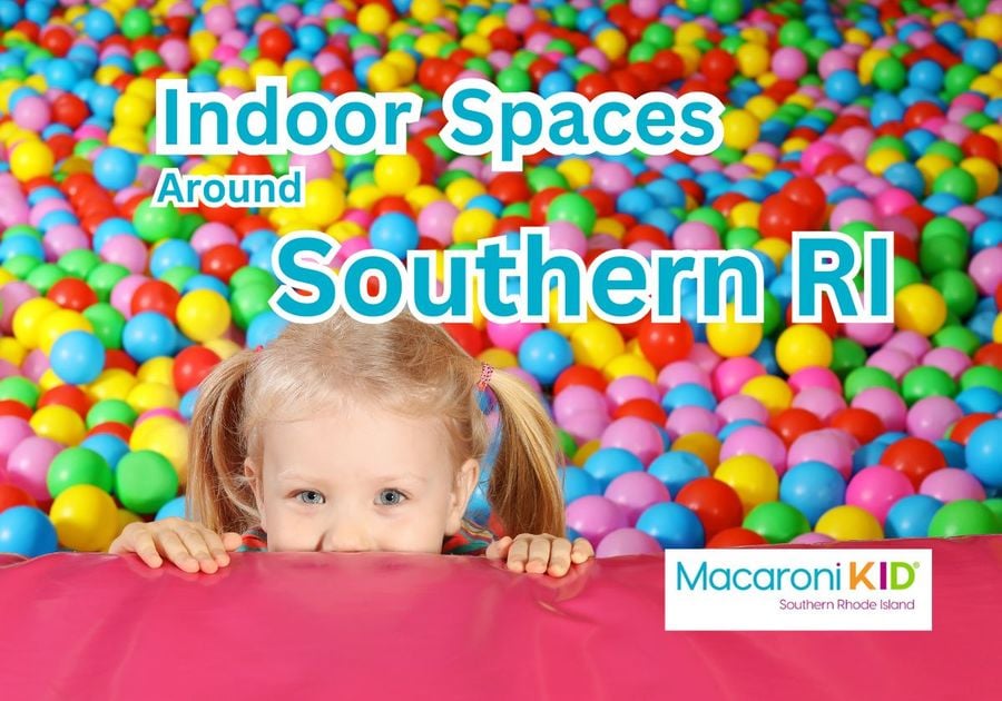 Young girl peeking over a play mat in a ball pit