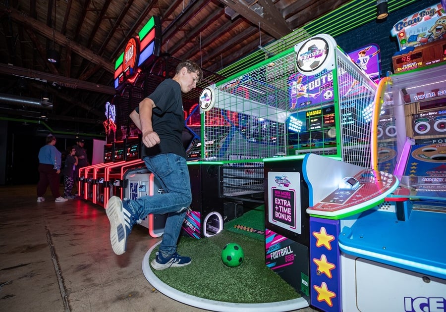 teen kicking ball in arcade game