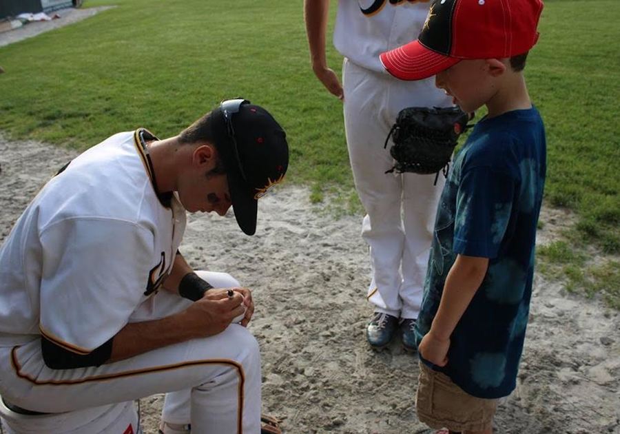 baseball player signs autograph for child