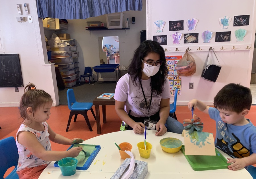 Teacher wearing face mask interacting with two preschool children at International School for Peace in Tucson